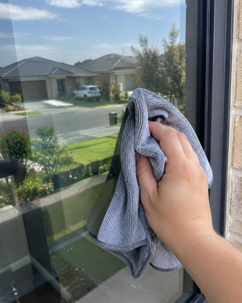 Customer wiping a window with a GenieCloth cloth